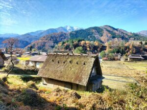 What to see in Shirakawa-go. A small house with a thatched roof and the mountains in the background.