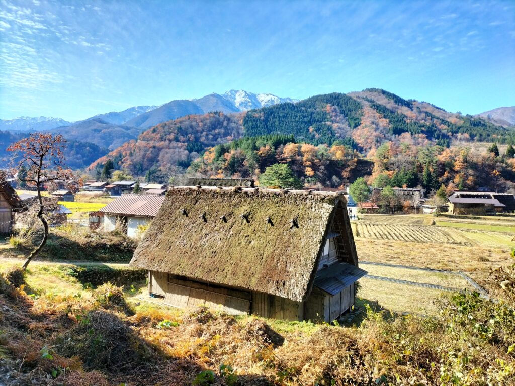 What to see in Shirakawa-go. A small house with a thatched roof and the mountains in the background.